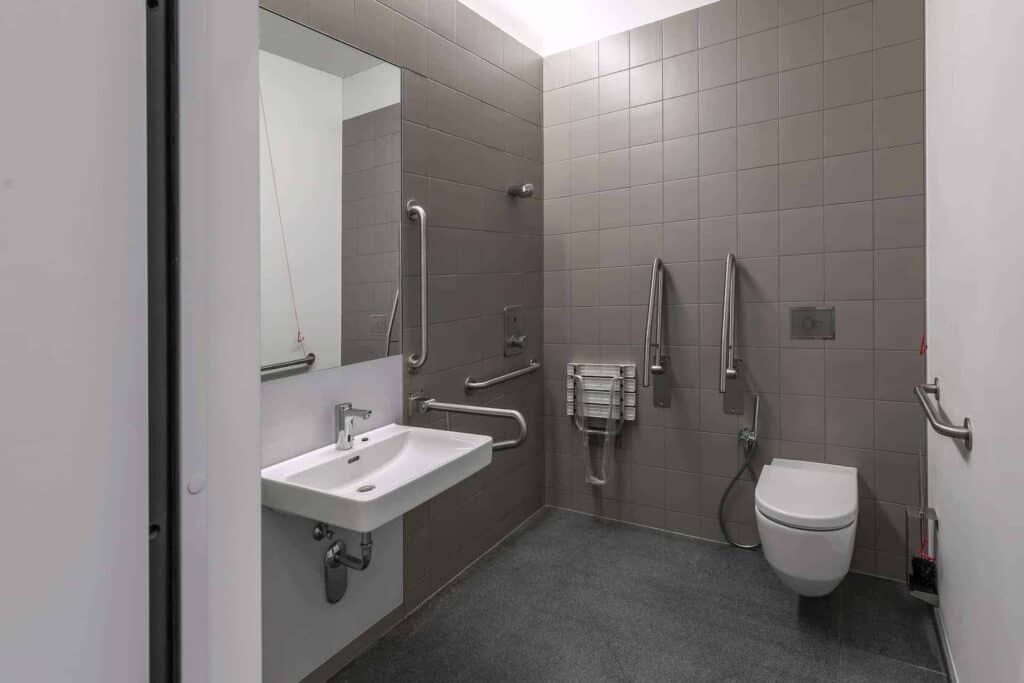 Handicapvenligt badeværelse med støttehåndtag og toilet.